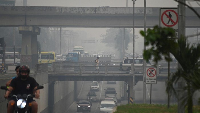People walk and drive through smoke caused by wildfires in the area, which prompted the local government to issue a red sanitary alert due to the heavy pollution, in Santa Cruz, Bolivia October 24, 2023. REUTERS/Claudia Belaunde NO RESALES. NO ARCHIVES