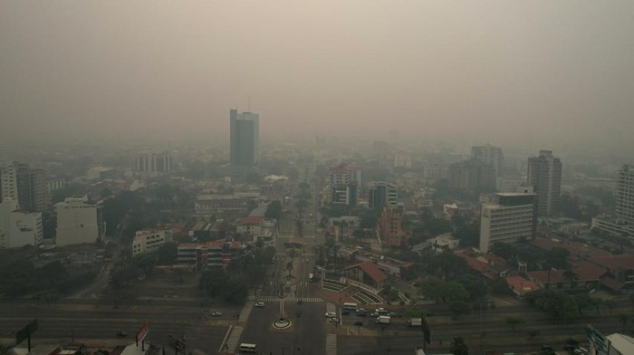People walk and drive through smoke caused by wildfires in the area, which prompted the local government to issue a red sanitary alert due to the heavy pollution, in Santa Cruz, Bolivia October 24, 2023. REUTERS/Claudia Belaunde NO RESALES. NO ARCHIVES