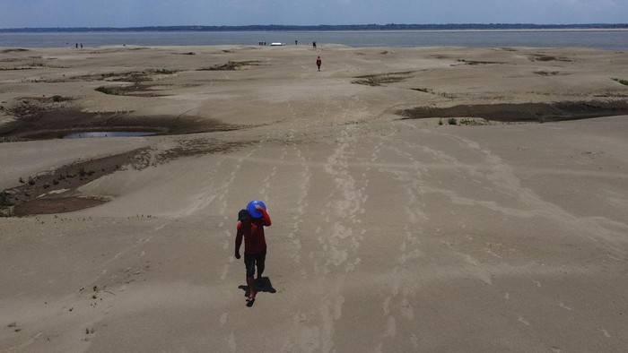 Residents of a riverside community carry food and containers of drinking water after being distributed by the state's humanitarian aid action due to the ongoing drought and high temperatures that affect the region of the Solimoes River, in Careiro da Varzea, Amazonas state, Brazil, Tuesday, Oct. 24, 2023. (AP Photo /Edmar Barros)