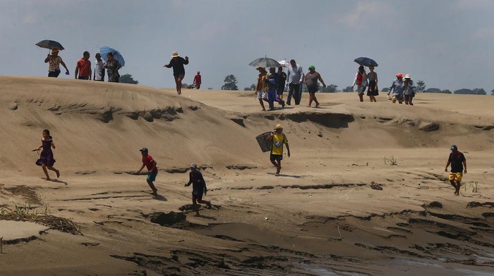 Kekeringan Parah, Sungai Amazon Berubah Jadi 'Savana' Residents of a riverside community carry food and containers of drinking water after being distributed by the state's humanitarian aid action due to the ongoing drought and high temperatures that affect the region of the Solimoes River, in Careiro da Varzea, Amazonas state, Brazil, Tuesday, Oct. 24, 2023. (AP Photo /Edmar Barros)