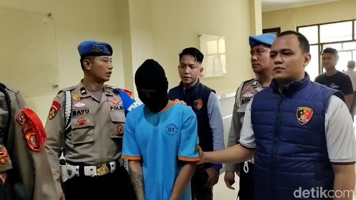 Peri Maulana (memakai sebo) saat digiring oleh polisi Cianjur. Peri merupakan pembunuh Ayu Lestari.