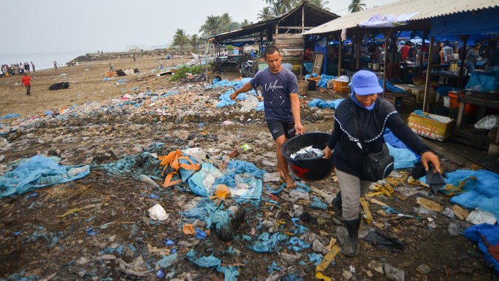 Pedagang membawa air melewati tumpukan sampah plastik di Tempat Pelelangan Ikan (TPI) Pasie Nan Tigo Padang, Sumatera Barat, Kamis (26/10/2023). Sampah plastik bekas pembungkus ikan tersebut berserakan dan bertumpuk di sekitaran pantai yang terdapat TPI dan pasar tradisional Banda Aia. ANTARA FOTO/Iggoy el Fitra/rwa.