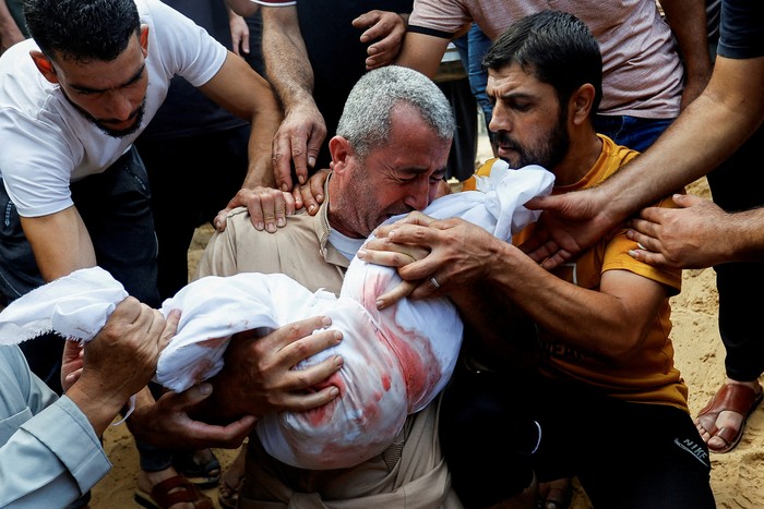 A mourner reacts while burying the body of a Palestinian child of al-Agha family, who was killed in Israeli strikes, in Khan Younis in the southern Gaza Strip October 11, 2023. REUTERS/Ibraheem Abu Mustafa     TPX IMAGES OF THE DAY