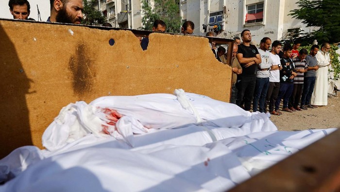 Mourners pray next to the bodies of Palestinians killed in Israeli strikes, during their funeral, as the conflict between Israel and Palestinian Islamist group Hamas continues, in Khan Younis, in the southern Gaza Strip, October 27, 2023. REUTERS/Ibraheem Abu Mustafa