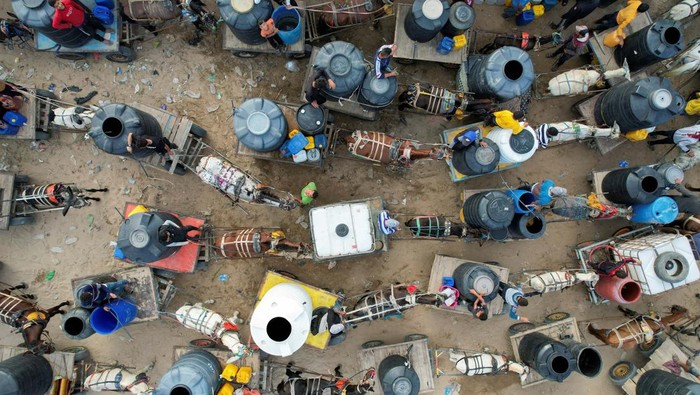 Sedih! Warga Gaza Minim Air Bersih di Tengah Gempuran Israel Palestinians with animal-drawn carts collect water from a water desalination plant, amid water shortages, as the conflict between Israel and the Palestinian Islamist group Hamas continues, in central Gaza Strip October 27, 2023. REUTERS/Mohammed Fayq Abu Mostafa