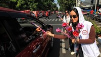 Relawan membagikan bunga mawar ke pengendara yang melintas di Jalan Diponegoro, Menteng, Jakarta, Sabtu (28/10/2023). 