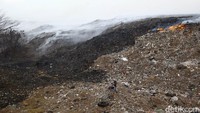 Seorang pemulung melintas di depan lautan sampah yang terbakar. TPA Rawa Kucing yang beroperasi sejak tahun 1992 mampu menampung sampah domestik/timbulan sampah sebesar 900-1.000 ton/hari dengan estimasi sampah yang dihasilkan dari rumah tangga sebanyak 400.000 KK.  