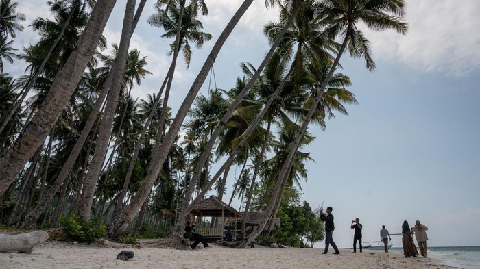 Pesona Wisata Pantai Poganda di Banggai Kepulauan Sejumlah wisatawan menikmati suasana pantai saat berwisata di Pantai Poganda, Desa Lukpanenteng, Kabupaten Banggai Kepulauan (Bangkep), Sulawesi Tengah, Minggu (29/10/2023). Hamparan pasir putih dengan rerimbunan pohon kelapa di sekitarnya dan ekosistem laut yang masih asli menjadi daya tarik tersendiri sehingga kawasan wisata alam pantai yang hanya dapat dijangkau dengan sarana transportasi laut ini menjadai salah satu tujuan wisata di wilayah itu. ANTARA FOTO/Basri Marzuki/nz