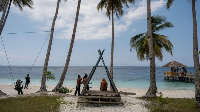 Pesona Wisata Pantai Poganda di Banggai Kepulauan Sejumlah wisatawan menikmati suasana pantai saat berwisata di Pantai Poganda, Desa Lukpanenteng, Kabupaten Banggai Kepulauan (Bangkep), Sulawesi Tengah, Minggu (29/10/2023). Hamparan pasir putih dengan rerimbunan pohon kelapa di sekitarnya dan ekosistem laut yang masih asli menjadi daya tarik tersendiri sehingga kawasan wisata alam pantai yang hanya dapat dijangkau dengan sarana transportasi laut ini menjadai salah satu tujuan wisata di wilayah itu. ANTARA FOTO/Basri Marzuki/nz