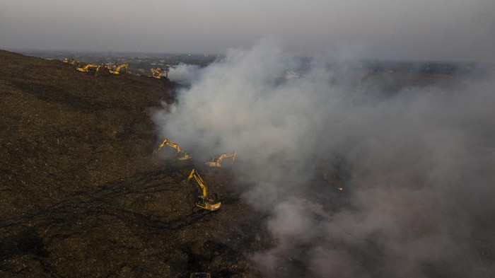 Sejumlah petugas menggunakan eskavator melakukan  proses pendinginan TPST (Tempat Pembuangan Sampah Terpadu) Bantargebang, Bekasi, Jawa Barat, Minggu (29/10/2023). Menurut keterangan Dinas Lingkungan Hidup (DLH) DKI Jakarta sebanyak 19 mobil pemadam dikerahkan untuk memadamkan api pada kebakaran yang terjadi pada pukul 13.30 WIB dan penyebab kebakaran di zona 2 TPST tersebut masih dalam penyelidikan. ANTARA FOTO/ Fakhri Hermansyah/nz