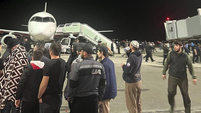 People in the crowd walk shouting antisemitic slogans at an airfield of the airport in Makhachkala, Russia, Monday, Oct. 30, 2023. Russian news agencies and social media say hundreds of people have stormed into the main airport in the Dagestan region and onto the landing field to protest the arrival of an airliner coming from Tel Aviv, Israel. (AP Photo)