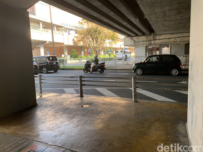 Pengendara motor Jepang antre lampu merah di belakang mobil
