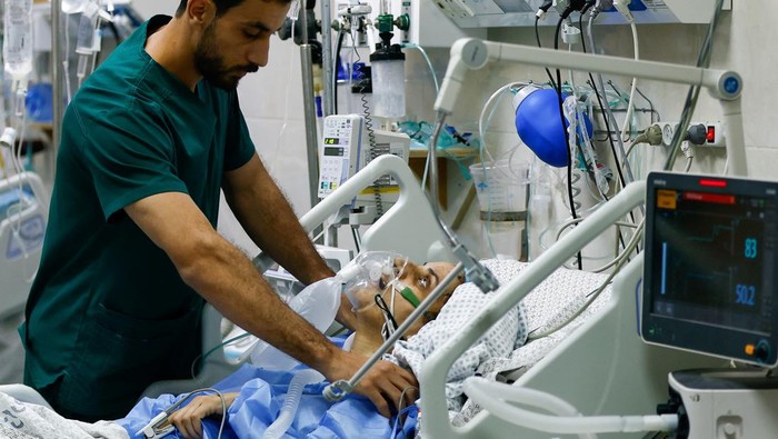 A medical worker assists a Palestinian, who was wounded in Israeli strikes, at the Intensive Care Unit (ICU) of Nasser hospital, as doctors say they are only able to accept critical cases that are in need of surgery, while the unit is filled up with victims of the ongoing conflict with Israel, in Khan Younis, in the southern Gaza Strip, October 26, 2023. REUTERS/Ibraheem Abu Mustafa