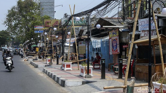 Pejalan kaki beraktivitas di trotoar depan Stasiun Bekasi, Senin (30/10/2023). Trotoar yang dibangun untuk pejalan kaki kini justru digunakan untuk parkir. Keberadaan bambu penyangga kabel-kabel yang masih bergantung di atas trotoar membuat trotoar ini kian semrawut.