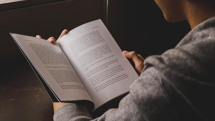 Membaca buku novel.