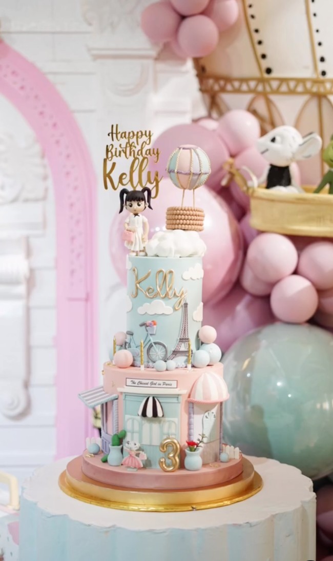 Kue ulang tahun Kelly yang terdiri dari 2 tingkat itu juga dibuat spesial sesuai dengan tema ulang tahunnya. Terdapat ornamen seperti balon udara, menara Eiffel, dan bangunan khas Paris. Usia dan nama Kelly juga tertera di kue ulang tahun tersebut. Foto: Instagram/@keziatoemion