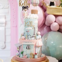 Kue ulang tahun Kelly yang terdiri dari 2 tingkat itu juga dibuat spesial sesuai dengan tema ulang tahunnya. Terdapat ornamen seperti balon udara, menara Eiffel, dan bangunan khas Paris. Usia dan nama Kelly juga tertera di kue ulang tahun tersebut. Foto: Instagram/@keziatoemion