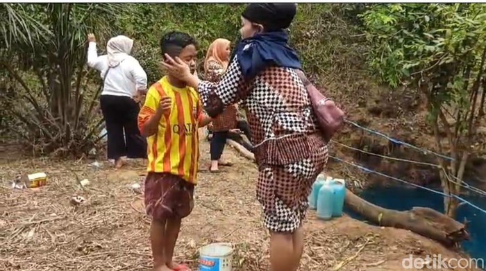 Warga menggunakan air telaga biru untuk membasuh bagian tubuh yang sakit.