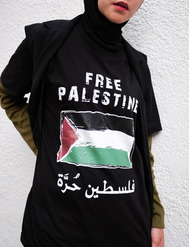Belakangan ku ga lagi jualan kaos. Jajan aja di ecomm nyari2… lagi rajin ku pakai buat statement & ingetin orang2 akan kebebasan Palestine yang dirindukan kami smua.. tulisnya pada caption foto. Foto: Instagram/@zaskiadyamecca
