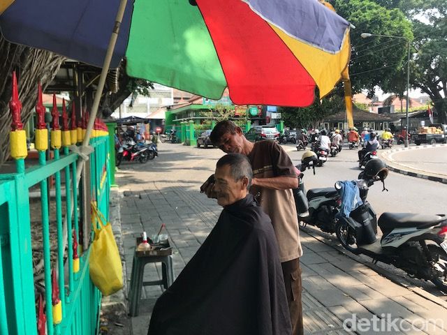 Aminudin atau Udin, yang membuka usaha pangkas rambut di bawah pohon beringin di sekitar Jalan Pangurakan, Ngupasan, Kecamatan Gondomanan, Kota Yogyakarta, saat ditemui Kamis (2/11/2023).