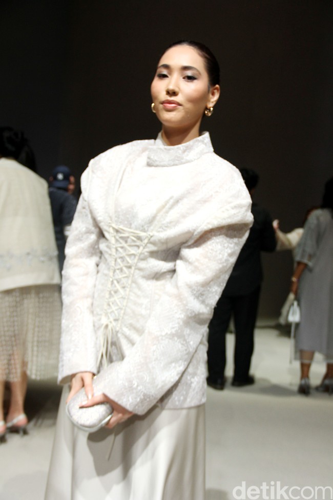 Puteri Indonesia 2022 Laksmi DeNeefe menebar pesonanya dalam padanan blus beraksen korset dengan kerah tinggi dan rok nude senada. (Foto: Mohammad Abduh/detikcom)