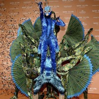 Tidak sendiri, Heidi membawa 10 orang lagi yang datang dari pemain sirkus. Para pemain sirkus itu dibuat seperti sayap merak raksasa dengan kaki dan lengan yang terangkat. Heidi pun berdiri di atas paha salah satu pemain akrobat. : Dok. Instagram/@heidiklum