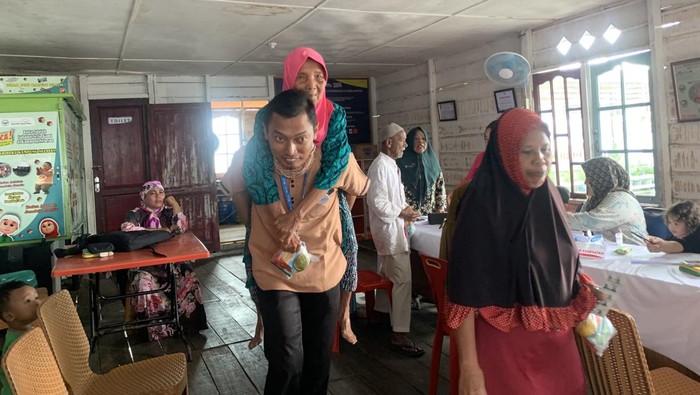 Nek Hanum digendong warga untuk melakukan cek kesehatan di Pos Amanah. (Kartika Sari/detikSumut)