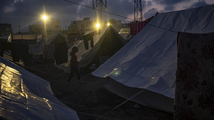 Potret Suasana Pengungsian Warga Palestina Saat Malam Tiba A Palestinian girl who was displaced by the Israeli bombardment of the Gaza Strip walks in a UNDP-provided tent camp in Khan Younis, Wednesday, Nov. 1, 2023. (AP Photo/Fatima Shbair)