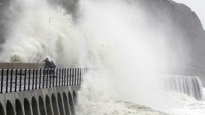 People run away from crashing waves at the promenade in Folkestone, England, Thursday, Nov, 2, 2023, as Storm Ciaran brings high winds and heavy rain along the south coast of England. (Gareth Fuller/PA via AP)