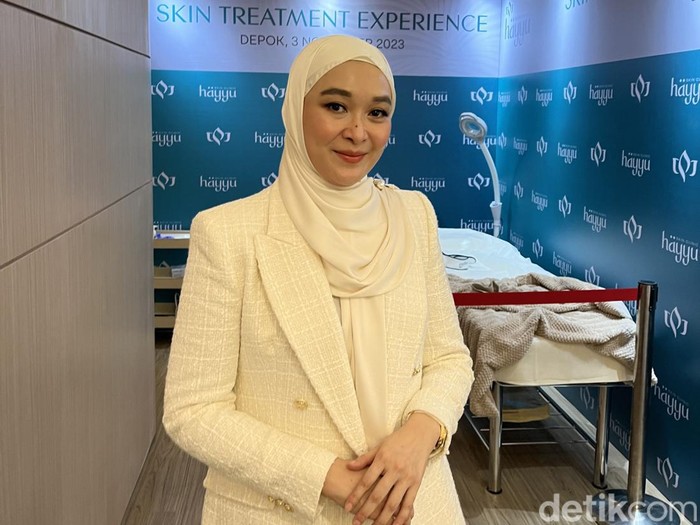 Photo of a young woman applying sunscreen on her face.