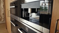 Selain itu, mereka juga punya microwave dan mesin espresso. Semuanya berwarna hitam dan tampak kontras dengan lemarinya yang warna cokelat. Foto: YouTube Architectural Digest