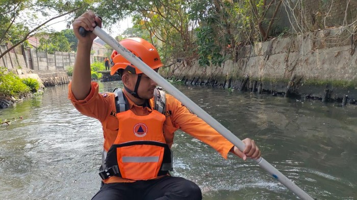 Sejumlah petugas BPBD Surabaya menelusuri sungai Medokan Semampir Indah untuk menelusuri buaya yang gegerkan warga.