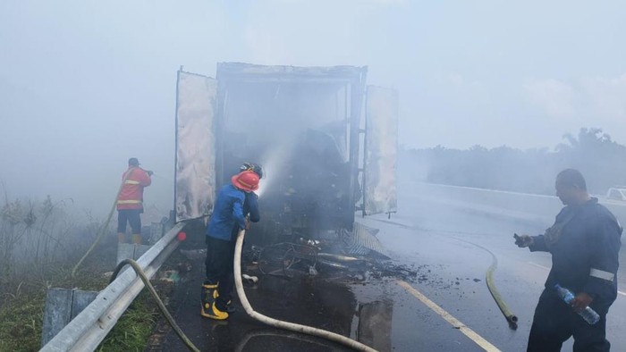 Petugas memadamkan api di trik tronton yang terbakar di tol Pekanbaru-Dumai. (Istimewa)