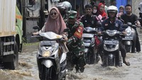 Prajurit TNI membantu pengendara motor saat melintasi banjir di Jalan Raya Pisangan, Desa Satria Jaya, Tambun Utara, Kabupaten Bekasi, Minggu (5/11/2023). ANTARA FOTO/ Fakhri Hermansyah