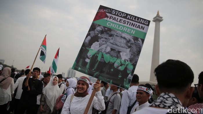 Massa memadati kawasan Monas, Jakarta Pusat di aksi bela Palestina. Bendera raksasa Palestina dibentangkan massa.