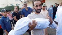 Seorang pria Palestina membawa jenazah seorang anak yang tewas dalam serangan Israel.