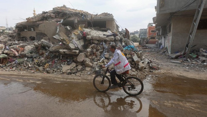 Palestinian doctor Hassan Zain al Din, who travels on his bicycle from one makeshift shelter to another to provide treatment and medication to displaced patients, rides past the rubble amid fuel shortages, as the conflict between Hamas and Israel continues, in Deir al-Balah, in the central Gaza Strip October 29, 2023. REUTERS/Ahmed Zakot