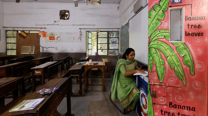 India Kembali Berlakukan Sekolah Online Gegara Polusi Udara A teacher conducts online classes in an empty classroom after primary schools were ordered shut by the Delhi government for Friday and Saturday as the air quality index (AQI) plummeted, on a smoggy morning in New Delhi, India, November 3, 2023. REUTERS/AnushreeΒ Fadnavis