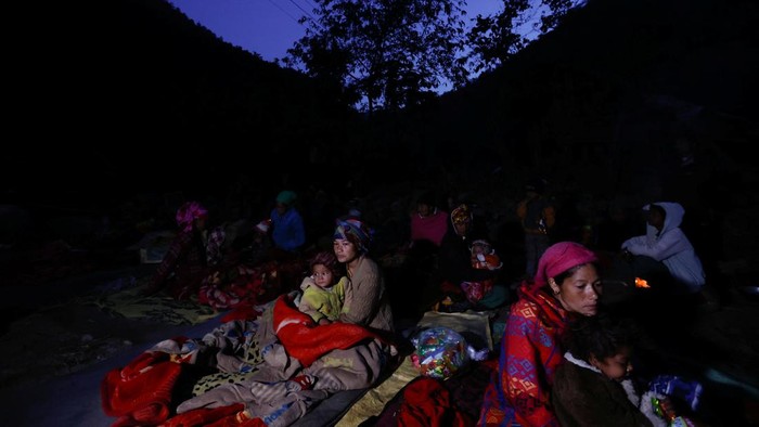 A family sits next to the fire to keep themselves warm early in the morning after spending the night out in the open after an earthquake in Rukum, Nepal November 5, 2023. REUTERS/Navesh Chitrakar