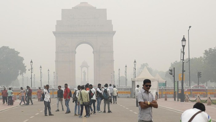 A man poses for a photograph in front of the landmark India Gate memorial in New Delhi, India, Friday, Nov. 3, 2023. Authorities on Friday shut primary schools and banned polluting vehicles and construction activity to control the worst haze and smog this season, causing respiratory infections among people and enveloping monuments and high-rise buildings in and around New Delhi. (AP Photo/Piyush Nagpal)