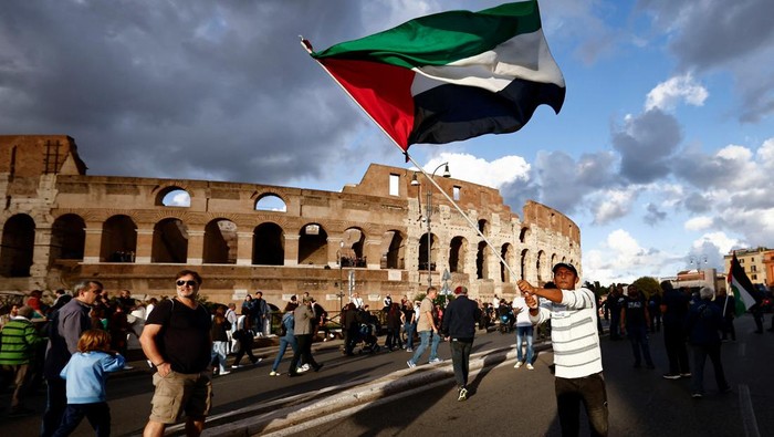 A man holds a Palestinian flag in front of the Colosseum during a demonstration in support of Palestinians in Gaza, as the conflict between Israel and the Palestinian Islamist group Hamas continues, in Rome, Italy, October 28, 2023. REUTERS/Yara Nardi