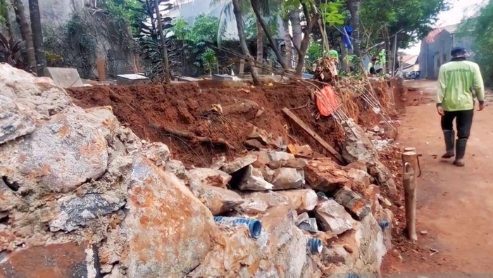 Tembok pembatas TPU di Cibubur, Jaktim, longsor dan menimpa rumah warga. Terjangan luapan kali juga membuat sejumlah makam amblas. (ANTARA/Syaiful Hakim)