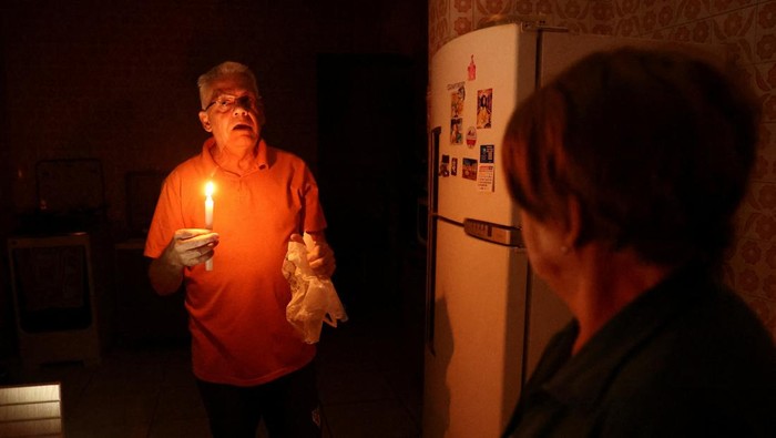 Badai Hantam Sao Paulo Brasil, Ratusan Ribu Orang Hidup Tanpa Listrik Jose Afonso Medeiros holds a candle as he talks to his wife, Ivone Medeiros, after more than seventy hours without electricity following a storm that knocked down power cables, in Sao Paulo, Brazil November 6, 2023. REUTERS/Carla Carniel
