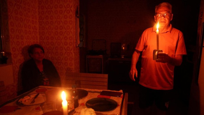 Jose Afonso Medeiros holds a candle as he talks to his wife, Ivone Medeiros, after more than seventy hours without electricity following a storm that knocked down power cables, in Sao Paulo, Brazil November 6, 2023. REUTERS/Carla Carniel