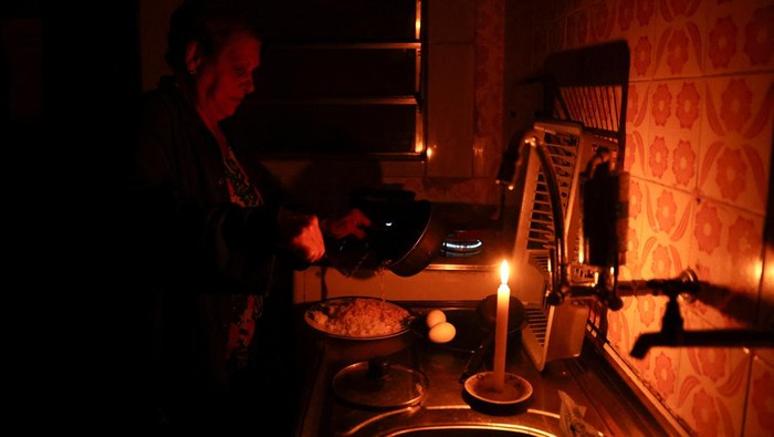 Jose Afonso Medeiros holds a candle as he talks to his wife, Ivone Medeiros, after more than seventy hours without electricity following a storm that knocked down power cables, in Sao Paulo, Brazil November 6, 2023. REUTERS/Carla Carniel