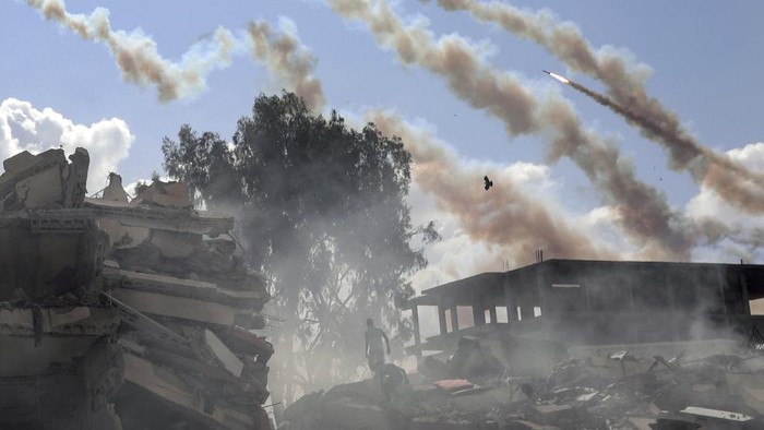 Rockets are fired from the Gaza Strip toward Israel over destroyed buildings following Israeli airstrikes on Gaza City, central Gaza Strip, Thursday, Oct. 19, 2023. (AP Photo/Mohammed Dahman)