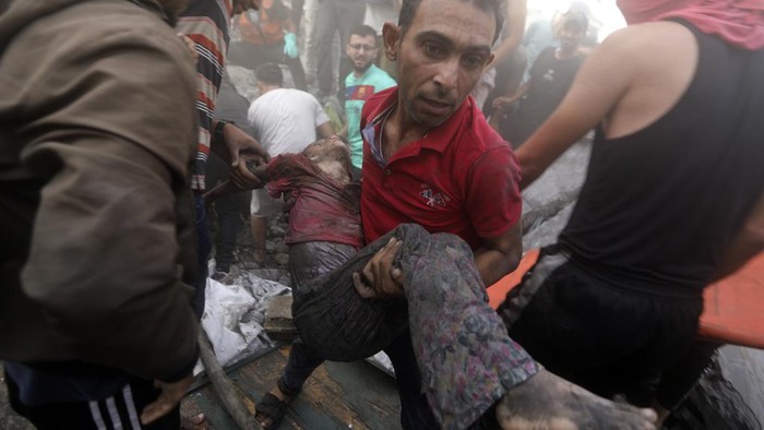 A Palestinian man carries a dead child that was found under the rubble of a destroyed building following an Israeli airstrike in Khan Younis refugee camp, southern Gaza Strip, Monday, Nov. 6, 2023. (AP Photo/Mohammed Dahman)