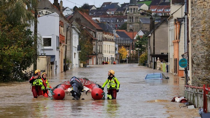 People stand on a flooded street as the La Liane River overflows in Saint-Etienne-au-Mont, near Boulogne-sur-Mer after heavy rain causing flooding in northern France, November 7, 2023. REUTERS/Pascal Rossignol