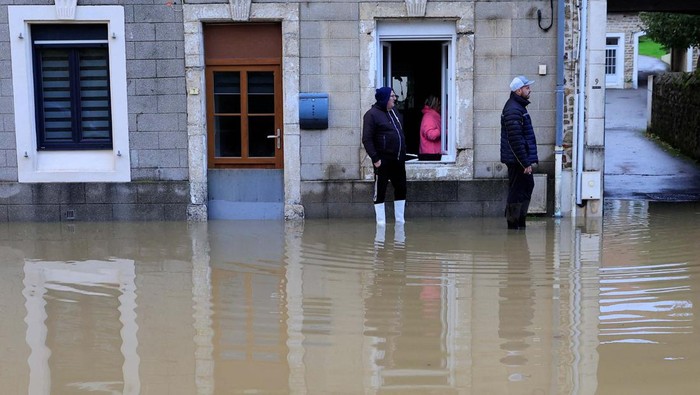 People stand on a flooded street as the La Liane River overflows in Saint-Etienne-au-Mont, near Boulogne-sur-Mer after heavy rain causing flooding in northern France, November 7, 2023. REUTERS/Pascal Rossignol