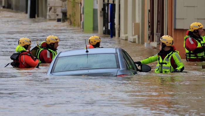 People stand on a flooded street as the La Liane River overflows in Saint-Etienne-au-Mont, near Boulogne-sur-Mer after heavy rain causing flooding in northern France, November 7, 2023. REUTERS/Pascal Rossignol